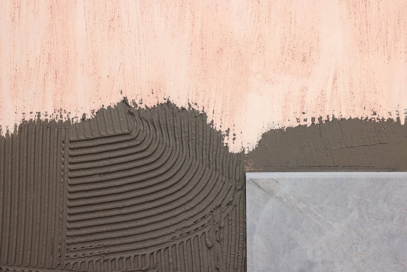 Tile adhesive being applied with trowel on wall