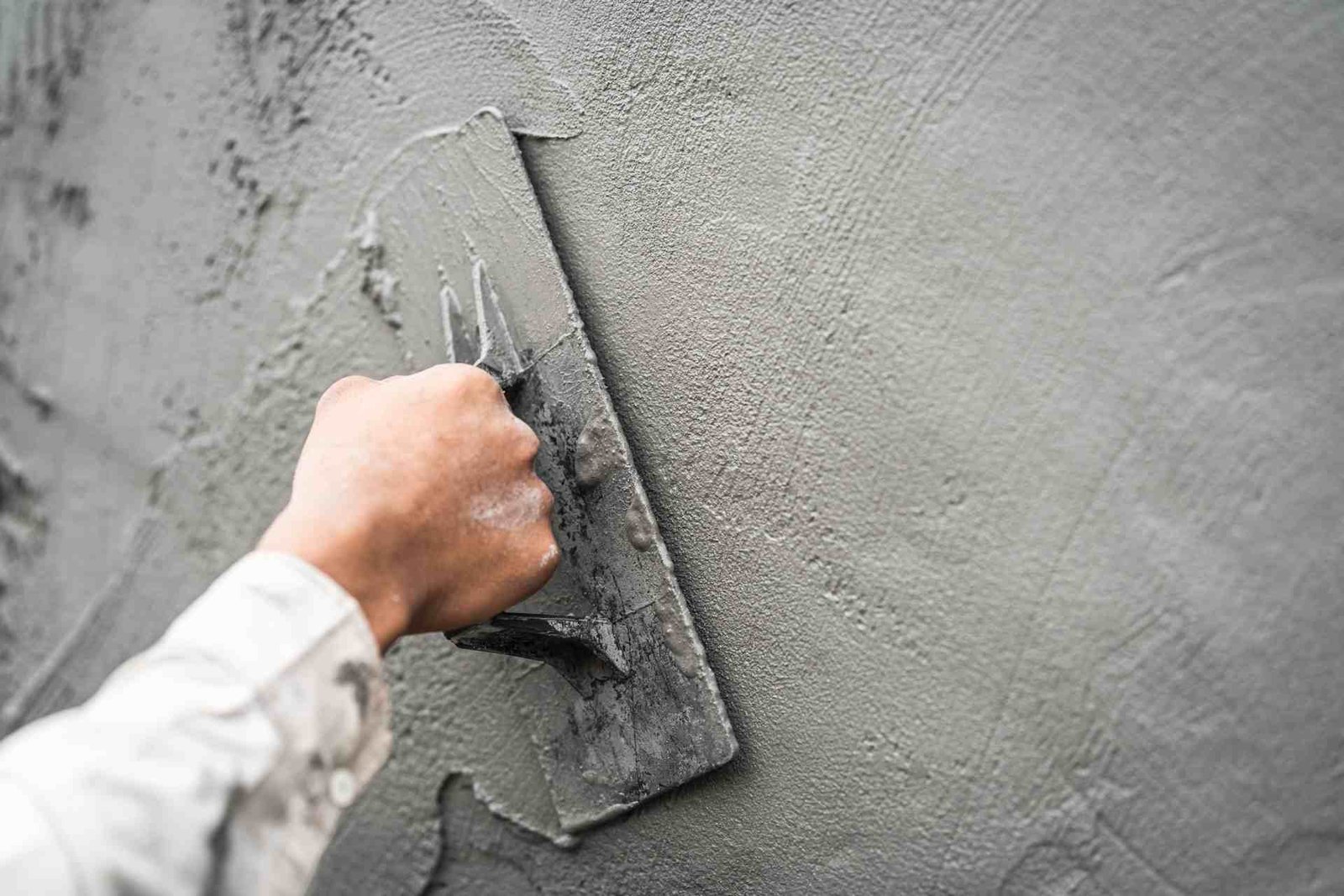 Construction worker applying cement mortar on a wall with trowel